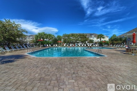 A large outdoor swimming pool surrounded by lounge chairs and umbrellas.