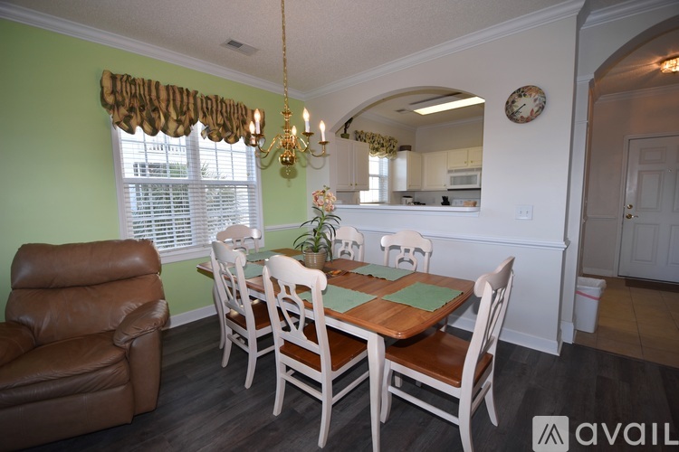 A dining room with a table set for six and a chandelier.