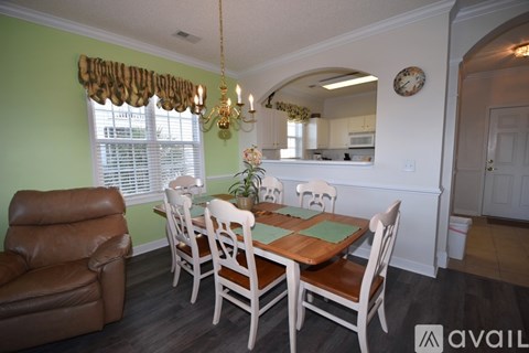 A dining room with a table set for six and a chandelier.