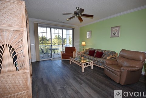 A living room with a brown leather couch, a wooden coffee table, and a ceiling fan.