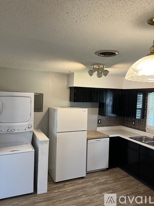 A kitchen with white appliances and black cabinets.