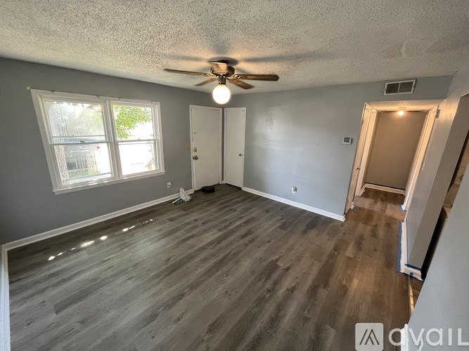 A room with a ceiling fan and wooden flooring.