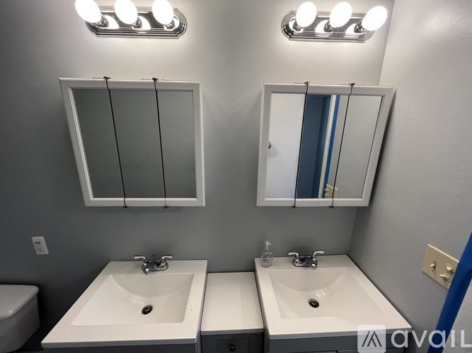 Two sinks under lights in a bathroom.