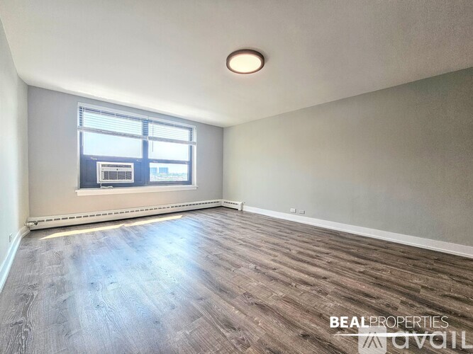A room with wooden flooring and a window with blinds.