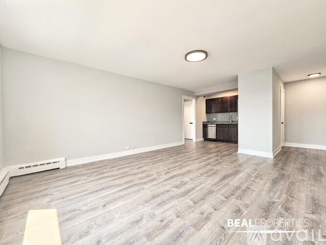 A spacious room with wooden flooring and white walls.