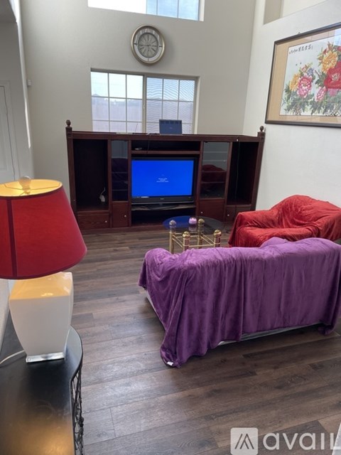 A living room with a purple couch and a red lamp.