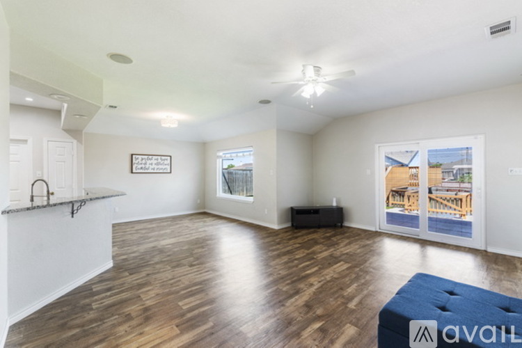 A spacious room with wooden flooring and a large window.