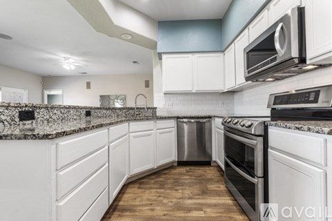 A kitchen with white cabinets and a granite countertop.