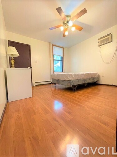 A room with a bed, a dresser, and a ceiling fan.