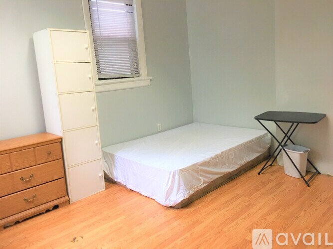 A bedroom with a bed, a dresser, and a small table.