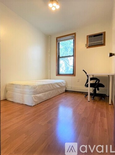 A room with a mattress, a chair, and a window.
