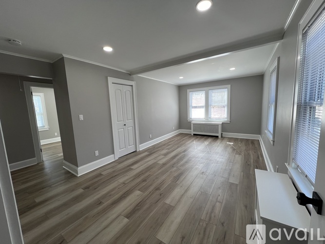 A spacious room with wooden flooring and a large window.