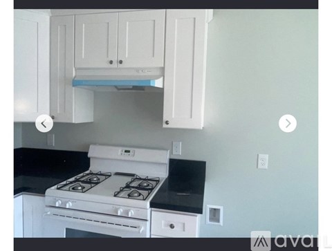 A white stove is in a kitchen with white cabinets.