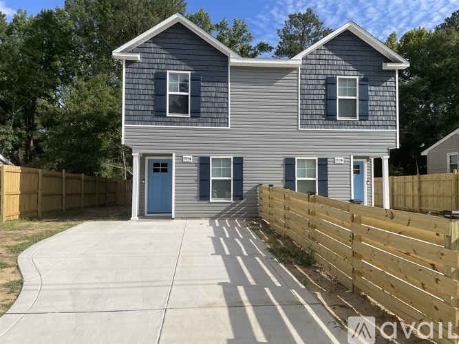 A grey house with a blue door and windows.