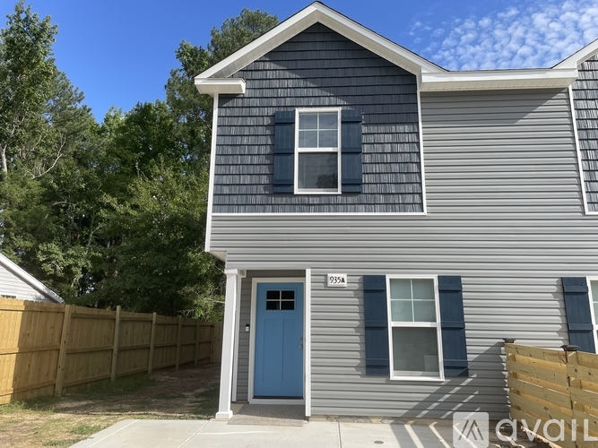 A house with a blue door and a grey facade is numbered 9254.