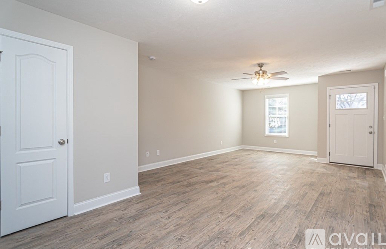 A room with a white door and a window with a ceiling fan.