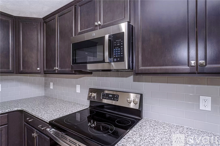A kitchen with a black stove top oven and a black microwave above it.