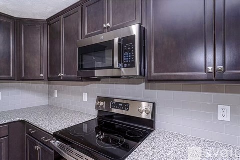 A kitchen with a black stove top oven and a black microwave above it.