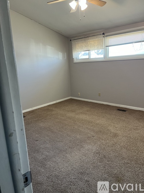 A room with a carpeted floor and a window with blinds.