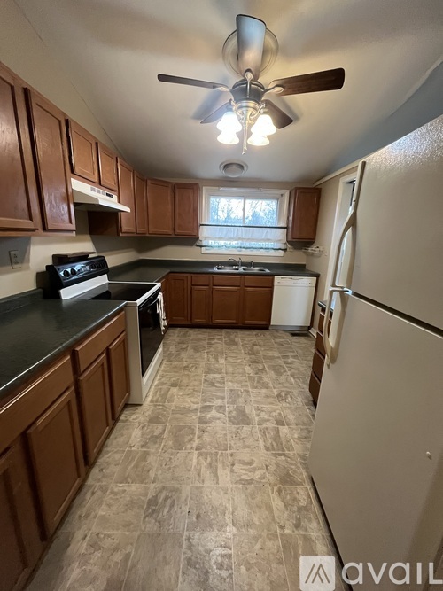 A kitchen with brown cabinets and a black countertop.