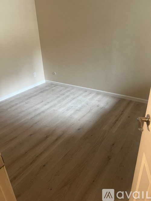 A room with wooden flooring and a door on the right side.