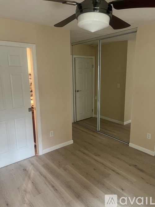 A room with a white door and a ceiling fan.