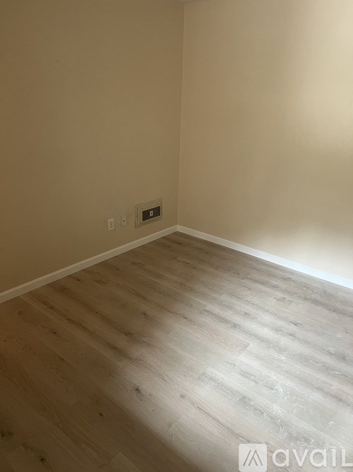 A room with wooden flooring and a light switch on the wall.