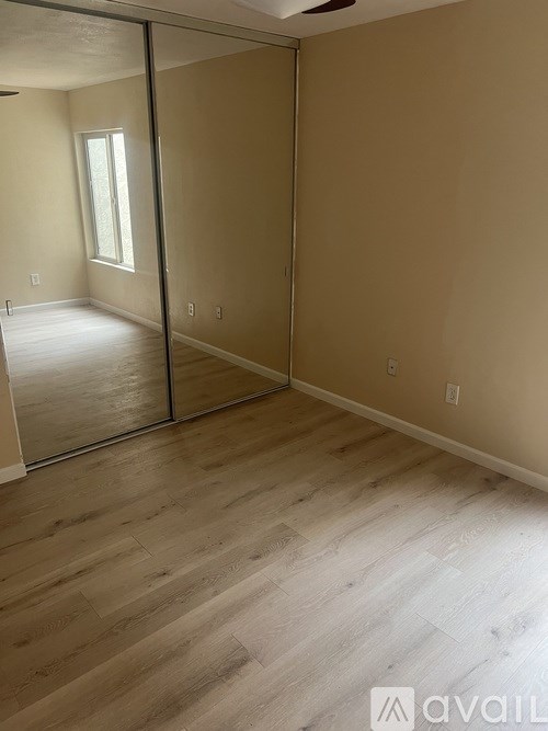 A room with a sliding glass door and wooden flooring.