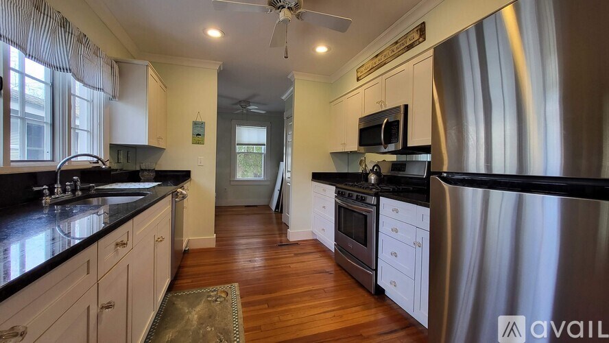A kitchen with white cabinets and black countertops.