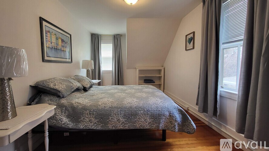 A bedroom with a bed, nightstand, and window.