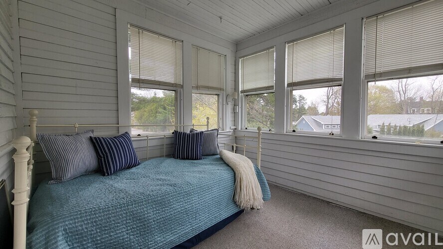A bedroom with a bed, pillows, and a window.