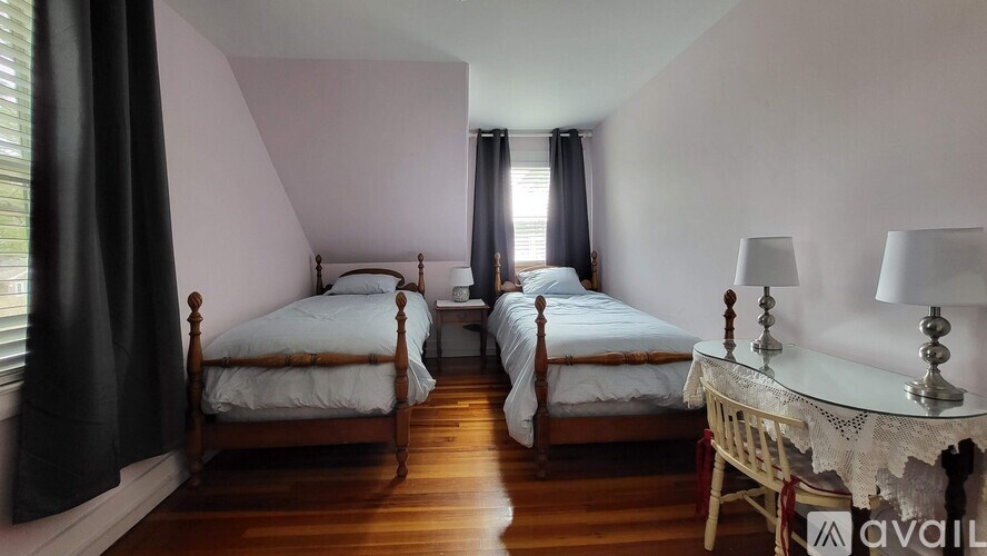 Two beds in a room with wooden floors and white walls.