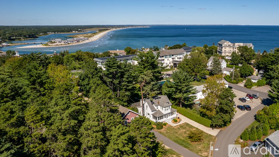 A bird's eye view of a coastal area with a beach, buildings, and trees.
