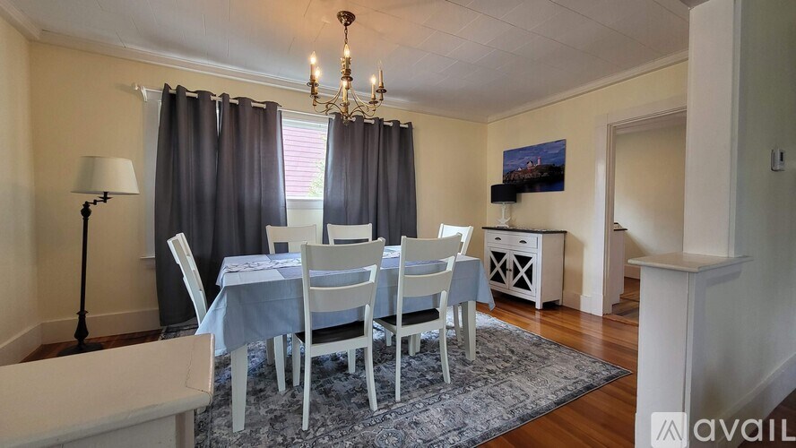 A dining room with a table set for six with blue tablecloths and white chairs.