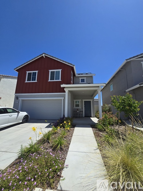 A red house with a white car parked in front.