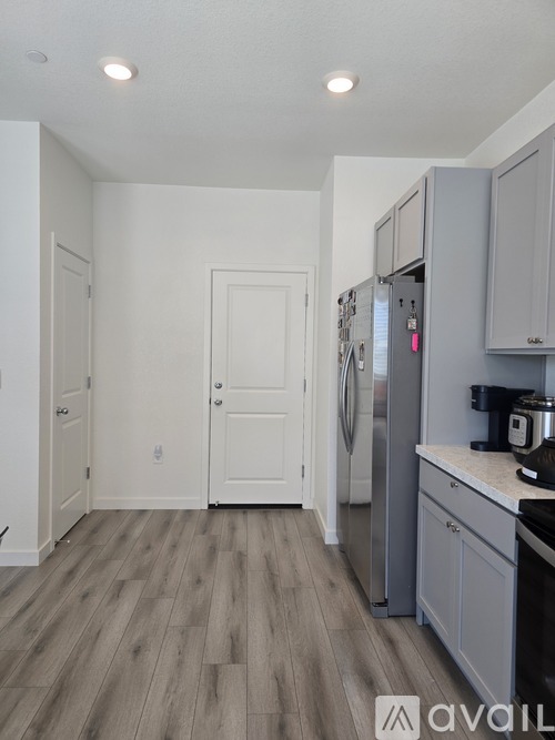A kitchen with a refrigerator, cabinets, and a countertop.