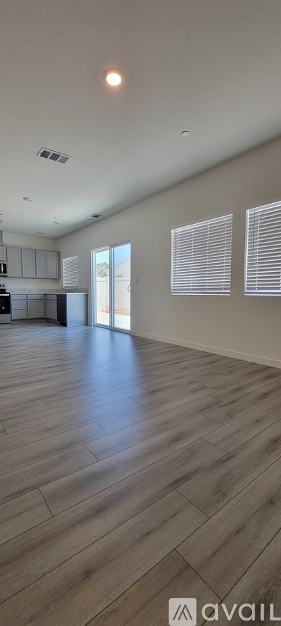 A spacious room with wooden flooring and white walls.