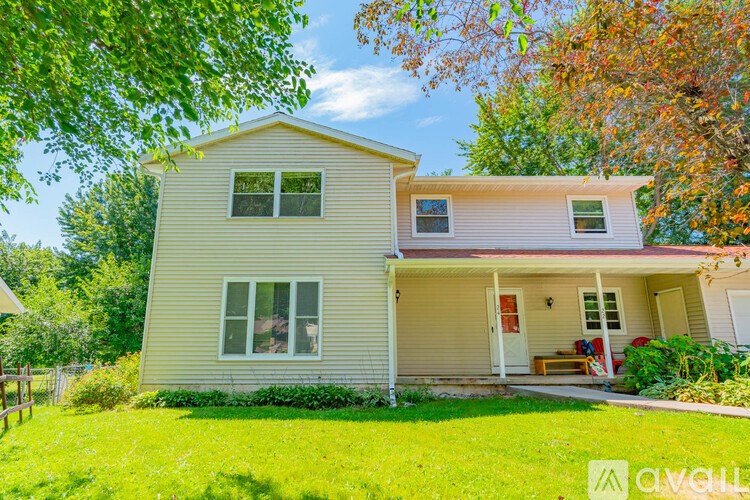 A house with a white door and windows is surrounded by greenery.