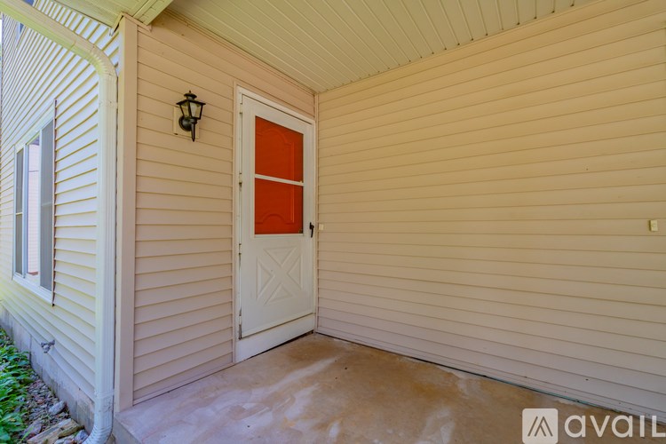 A white door with a red panel is on a beige house.