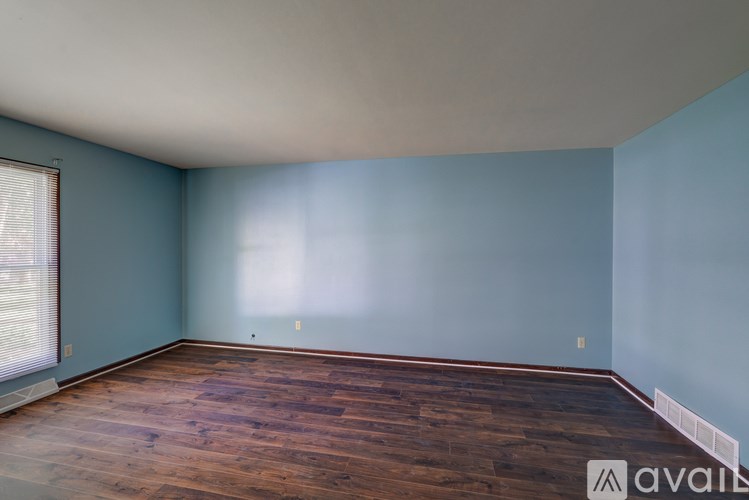 A room with wooden flooring and a window with blinds.