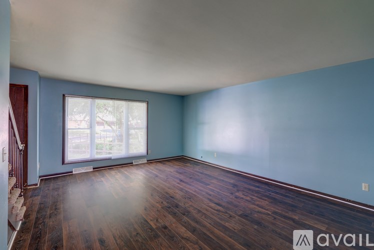 A room with wooden floors and a window with blinds.