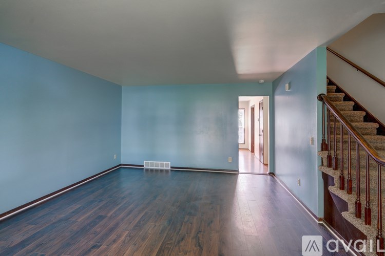 A room with wooden floors and a staircase with red railings.