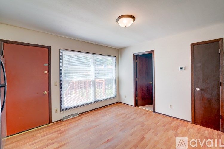 A room with wooden floors and a large window with a view of a balcony.