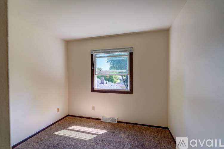 A room with a window showing a view of a street and houses.