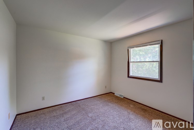 A room with a window and carpeted floor.