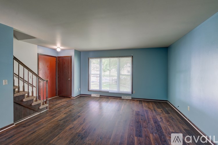 A room with wooden floors and a staircase leading to the upper level.