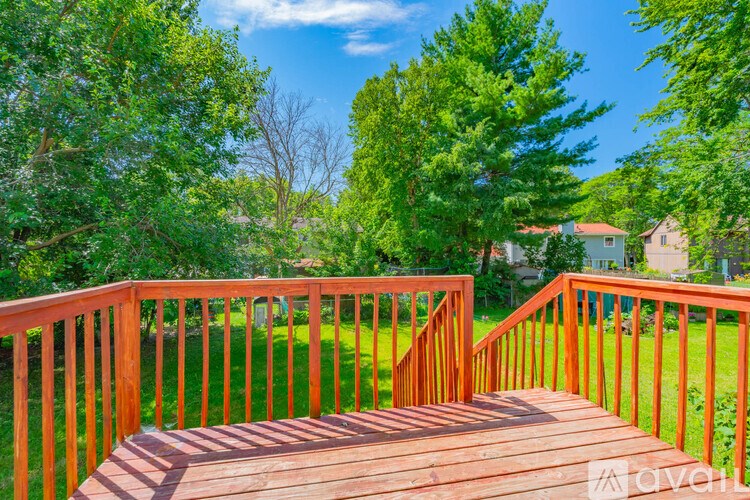A wooden deck leads to a lush green backyard.
