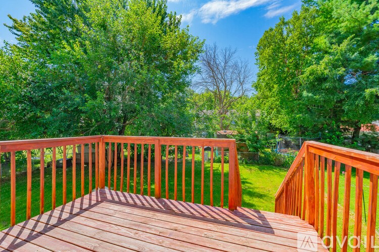 A wooden deck overlooks a lush green yard.