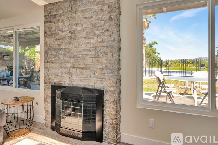 A modern living room with a stone fireplace and a view of the outdoors.