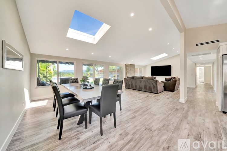 A modern dining room with a table set for four and a skylight above.
